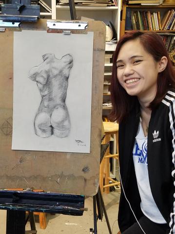 Student with charcoal figure drawing.